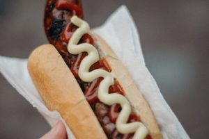 person holding hotdog sandwich with ketchup